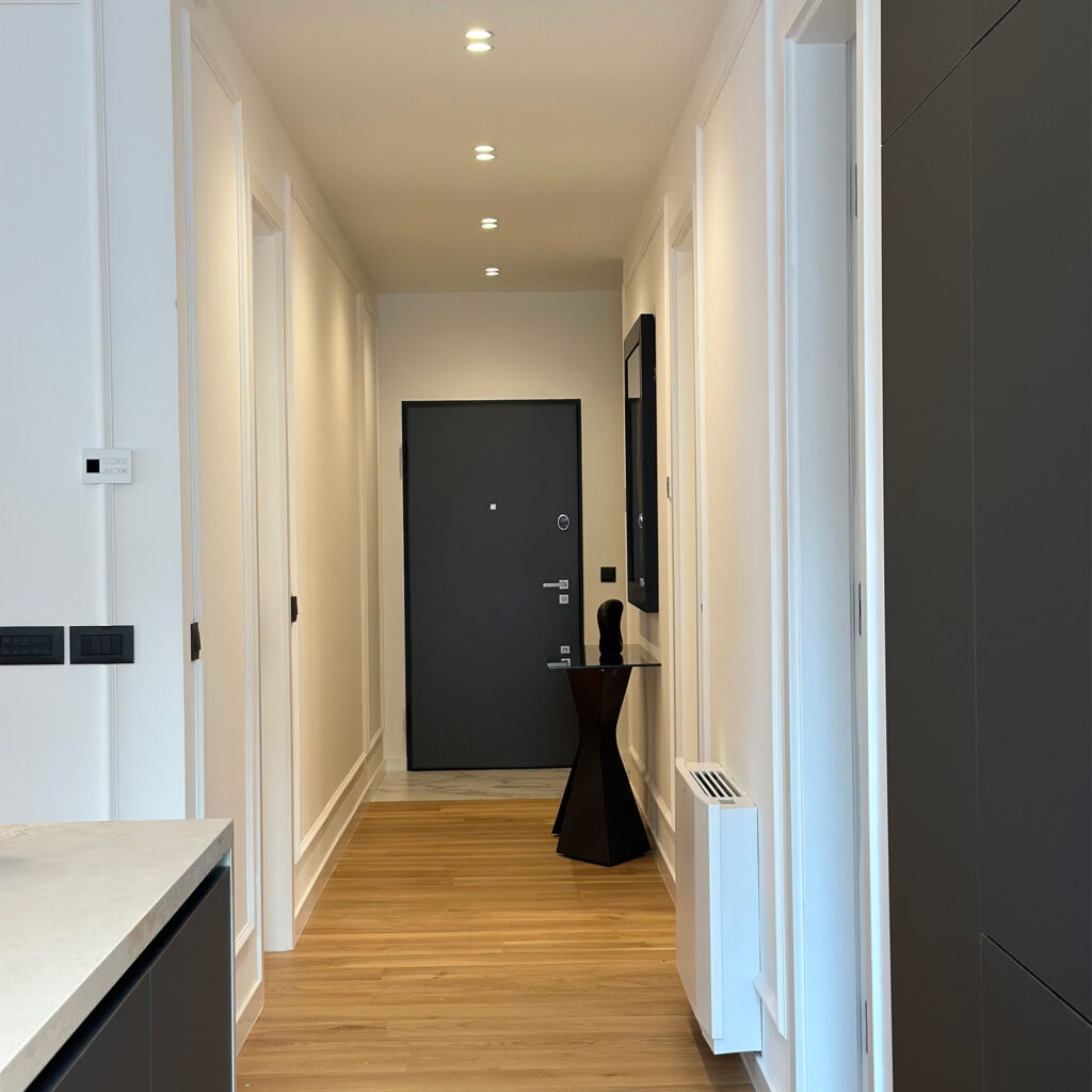 Minimalistički i profinjen hodnik s toplim drvenim tonovima i diskretnim rasvjetnim detaljima, koji pruža elegantan uvod u ostatak doma.
